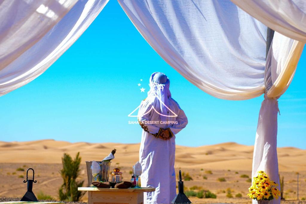 伊尔富德Sahara Desert Camping Merzouga & Erg Chebbi Dunes的站在沙漠帐篷下的女人