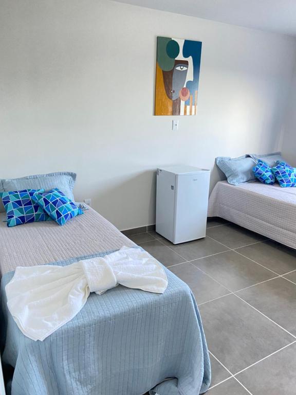瓜拉派瑞Hanuá Beach House的一间带两张床和小冰箱的卧室