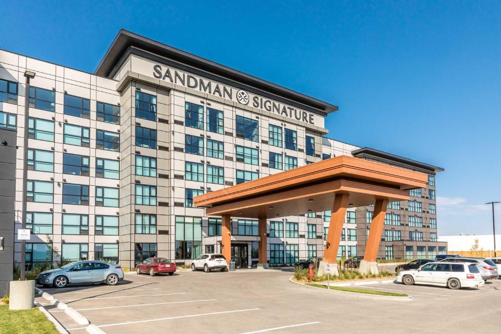 萨斯卡通Sandman Signature Saskatoon South Hotel的停车场内停放汽车的大型建筑