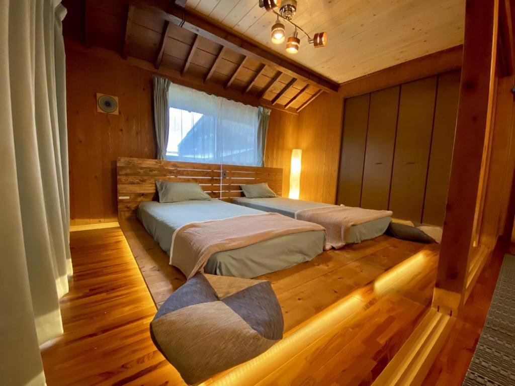 奄美Yamato inn - Vacation STAY 86368v的一间卧室设有两张床和窗户。