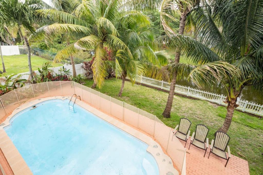彭布罗克派恩斯Waterfront 2-Story Villa with Heated Pool的一个带两把椅子的游泳池,棕榈树