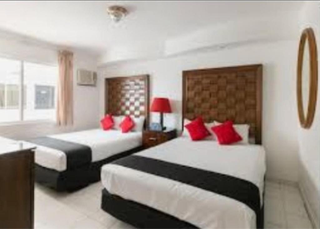 马萨特兰Zona Dorada Suites的酒店客房 - 带两张带红色枕头的床
