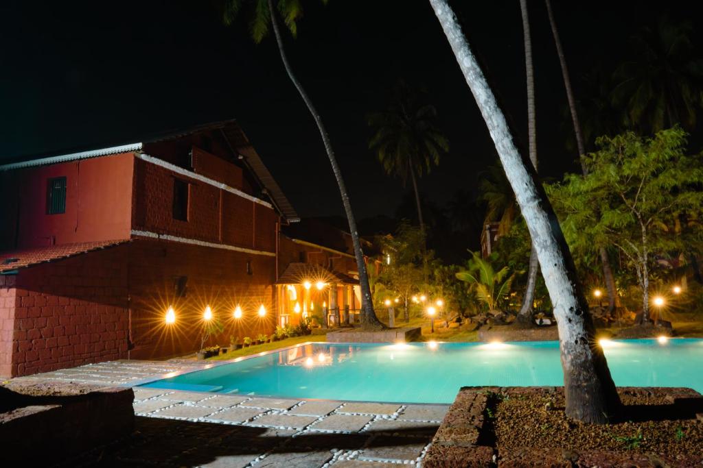 SawantwadiSawantwadi Palace Boutique Art Hotel的一座游泳池,在晚上在建筑物前