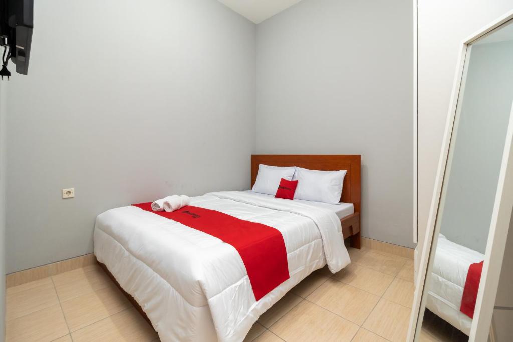 当格浪RedDoorz near RS Sari Asih Cipondoh的一间卧室配有一张带红白毯子的床