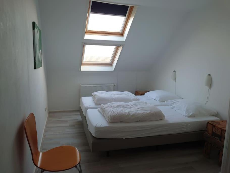OosterendDe Oostkamer; Eiland appartement naast natuurgebied Boschplaat的一间卧室配有两张床和椅子