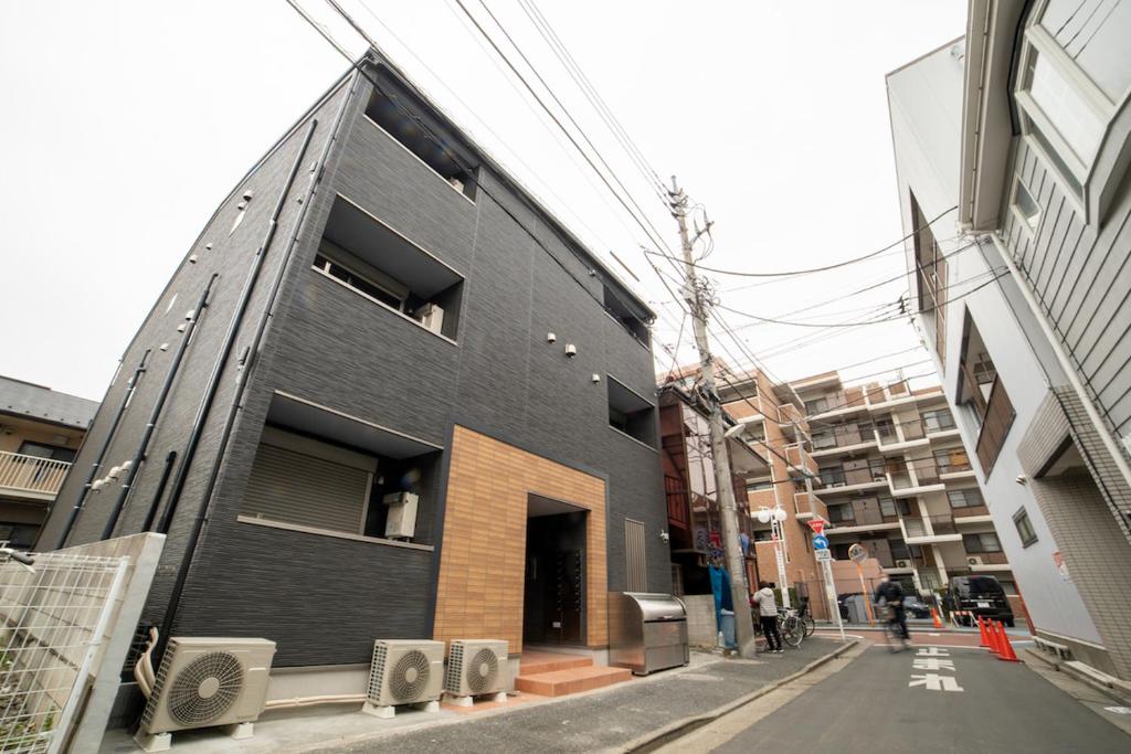 东京ミニマリズムホテル葛飾的街道边的黑色建筑