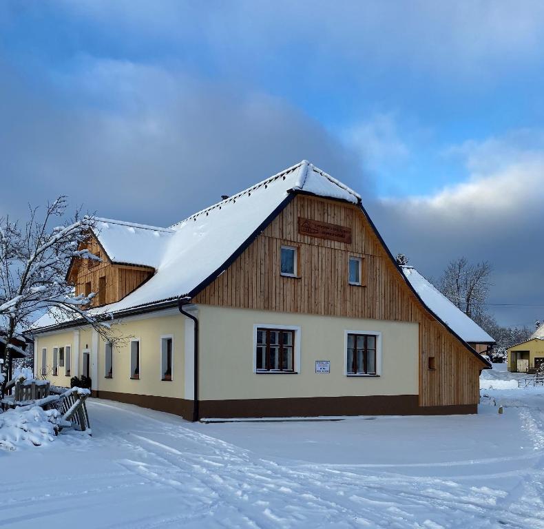 诺夫梅斯托纳马瑞夫Penzion Stanice lyžařů Fryšava的一座大木屋,屋顶上积雪