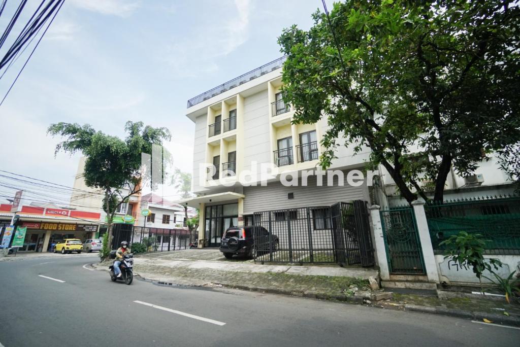 雅加达Toba Mansion Syariah near Benhil RedPartner的骑摩托车的人在建筑物前的街道上骑摩托车