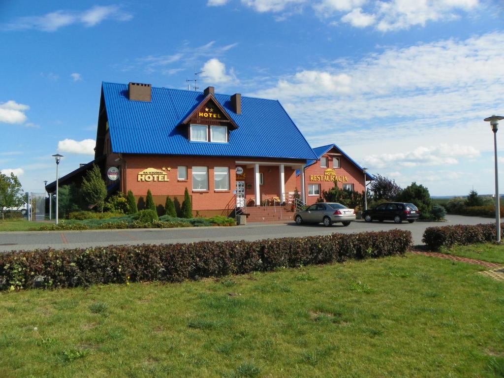 格涅夫Hotel Na Wzgórzu的一座蓝色屋顶的房子和停在前面的汽车