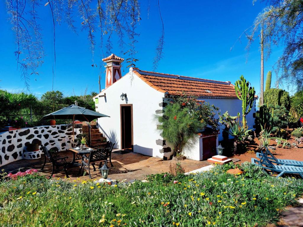 Garafía埃尔加罗度假屋的一座白色的小建筑,配有桌子和雨伞