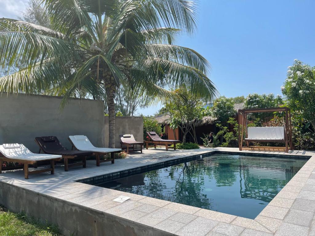 贝岛maison vanilianadia的一个带椅子的游泳池,并种植了棕榈树