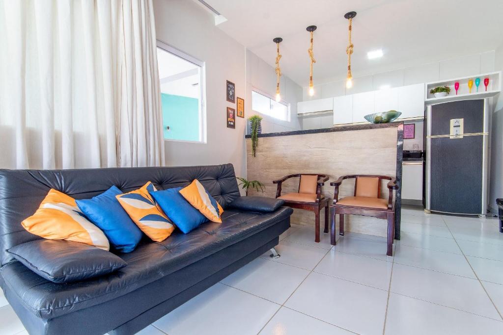 尼西亚弗洛雷斯塔Incrível casa na Praia de Camurupim por Carpediem的客厅配有黑色皮沙发,提供蓝色和橙色枕头