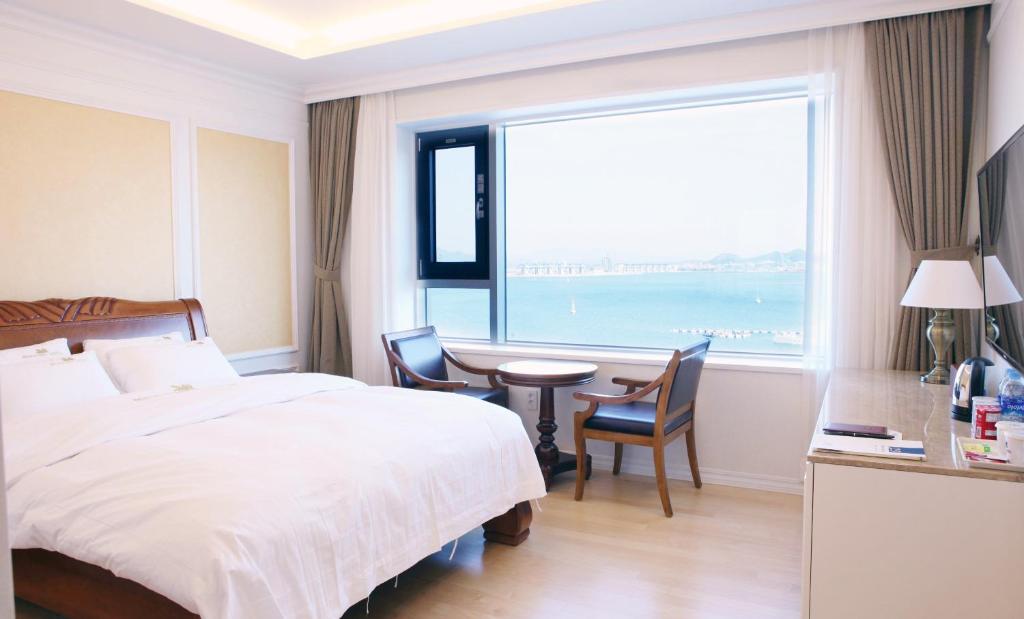 木浦市丰塔纳海滩酒店的一间卧室配有一张床、一张书桌和一个大窗户