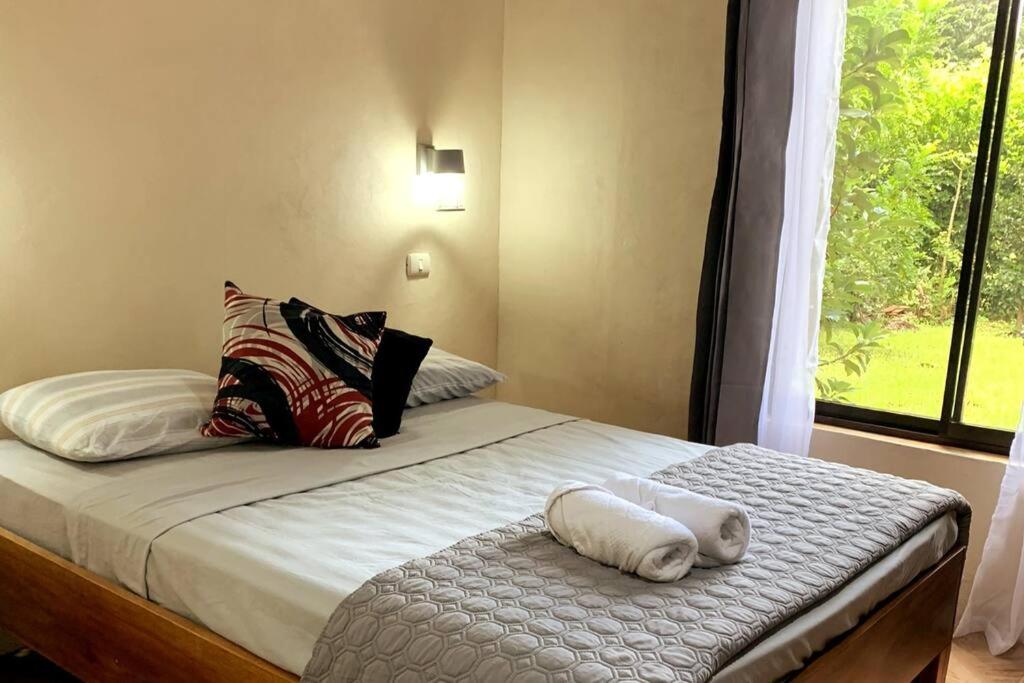 圣克鲁斯Miniapartamento el Guanacaste, cerca Tamarindo的卧室配有带枕头的床铺和窗户。