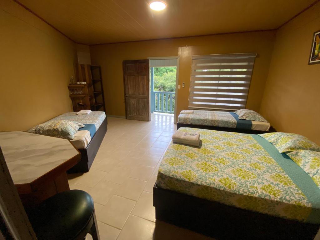蒙特苏马Hotel Ticozuma的带三张床、桌子和窗户的房间