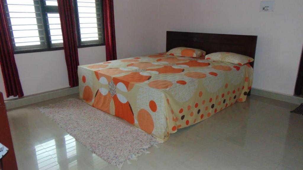GonikoppalShree Raksha Homestay的窗户客房内的橙色和白色床铺
