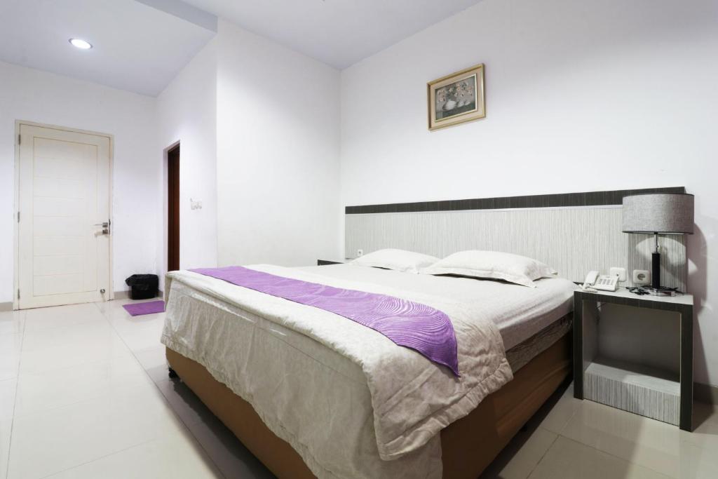 北干巴鲁Paus Guest House Pekanbaru的一间白色客房内配有一张大床的卧室