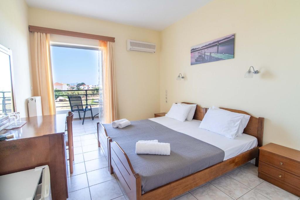 米提卡斯Iraklis Hotel的一间卧室配有一张床、一张桌子和一个窗户。