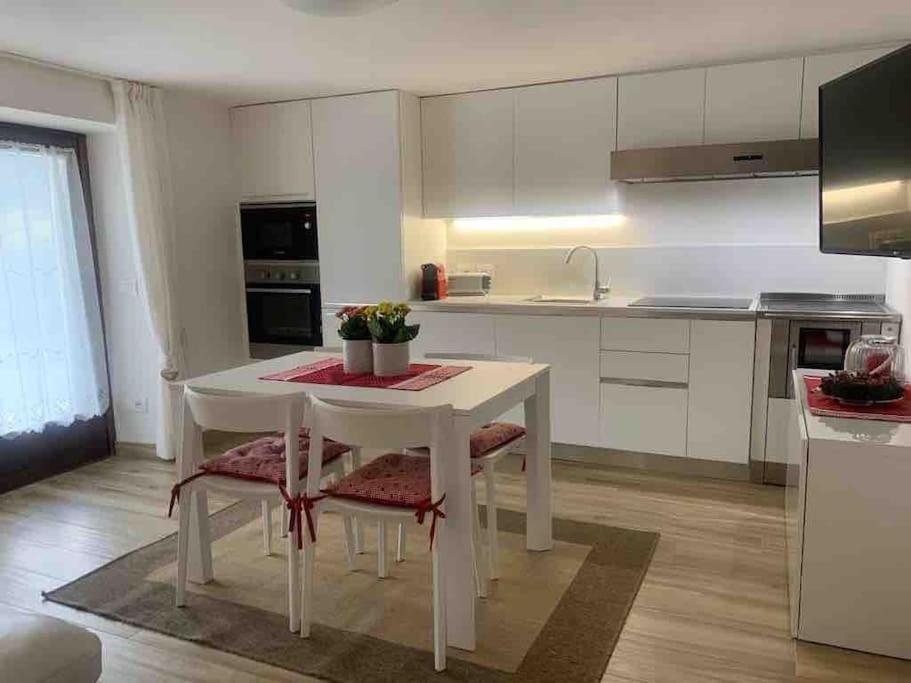 平佐洛Pinzolo, grazioso appartamento, wellness a 100 metri的白色的厨房配有白色的桌子和椅子