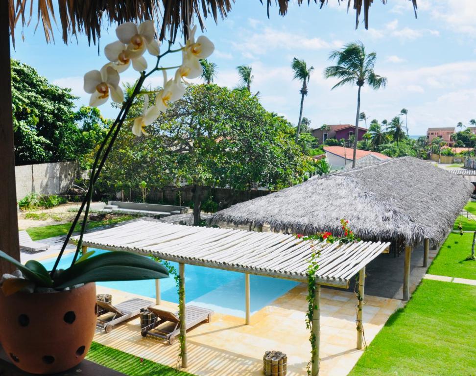卡姆布库Pousada Casa Caju Bangalows的一个带游泳池和草伞的度假胜地