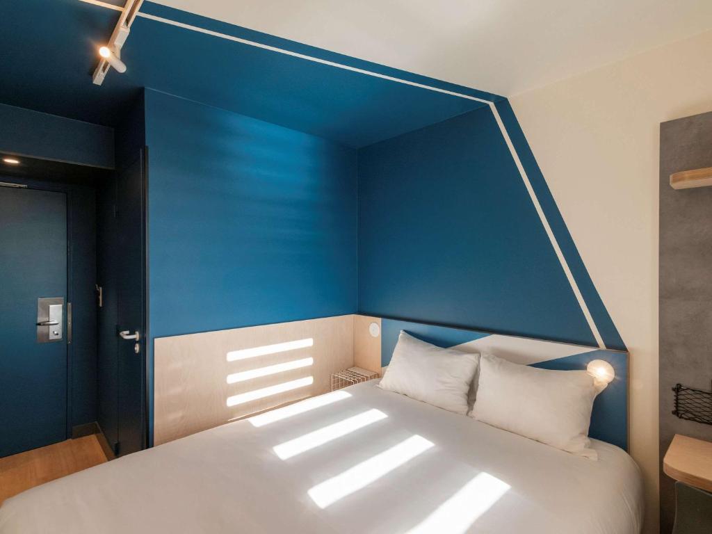 里昂里昂市中心康弗路恩斯宜必思快捷酒店的一间卧室设有一张蓝色墙壁的大床