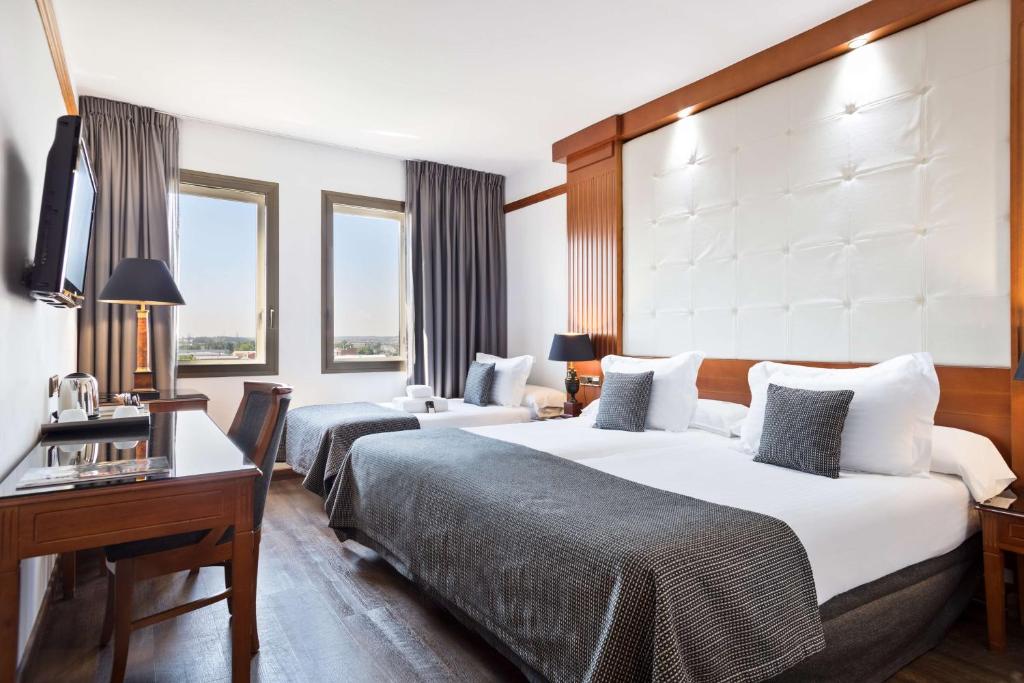 赫罗纳Best Western Premier CMC Girona的酒店客房配有两张床和一张书桌