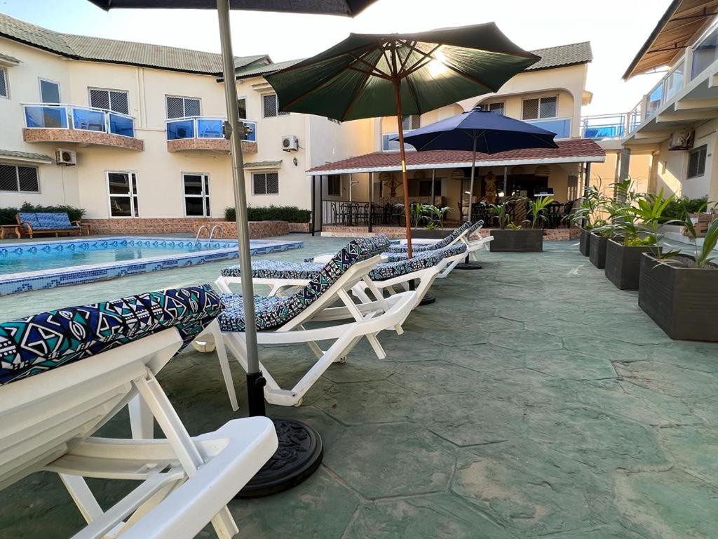 BrusubiTRANQUIL RESORT HOTEL的游泳池旁一排带遮阳伞的躺椅