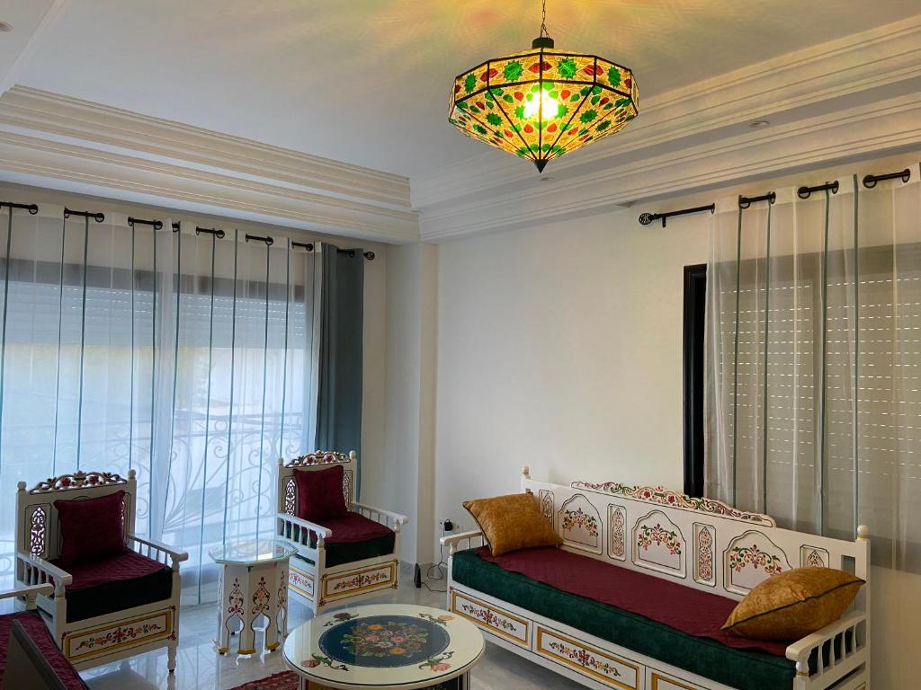拉马萨Marsa Authentic Luxury Appart 1的一间卧室配有一张床、两把椅子和一个吊灯