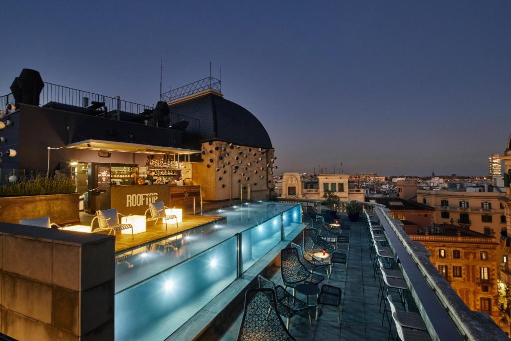 巴塞罗那巴塞罗那奥拉酒店的大楼内屋顶酒吧,配有桌椅