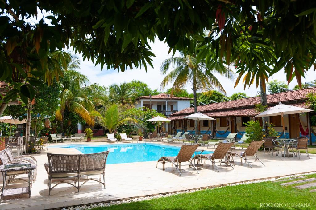 伊塔乌纳斯Pousada Estalagem Vila Tania的度假村的游泳池,配有椅子和遮阳伞