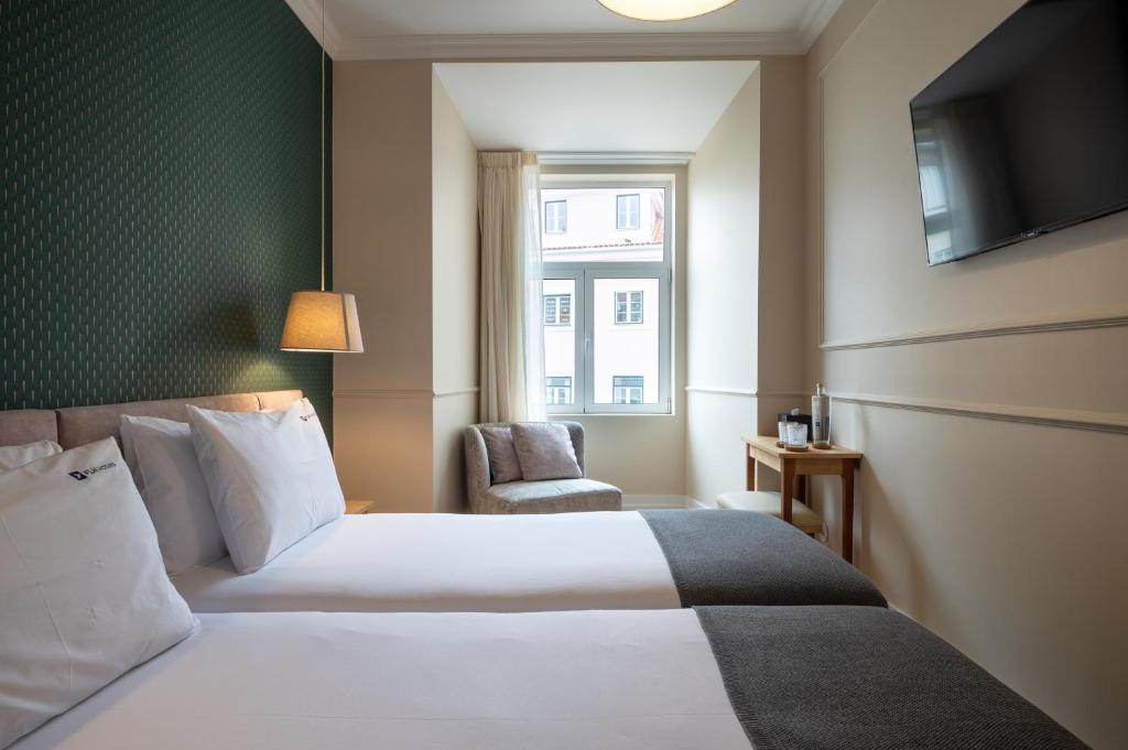 里斯本Rossio FLH Suites的配有一张床和一把椅子的酒店客房