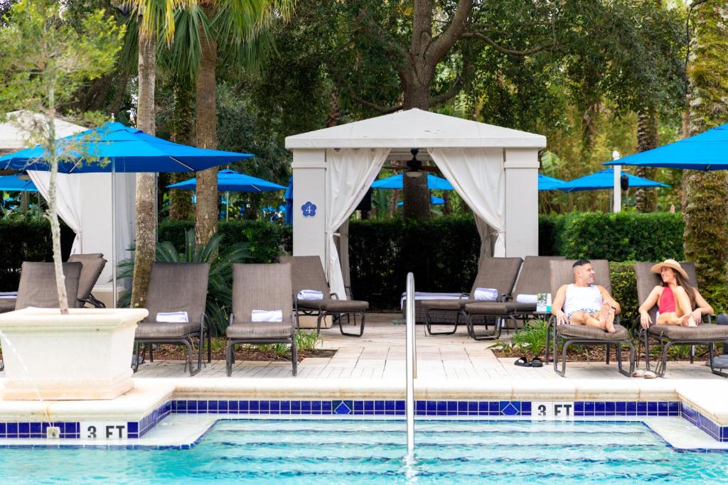 基西米冠军门欧尼酒店的两人坐在游泳池旁的椅子上