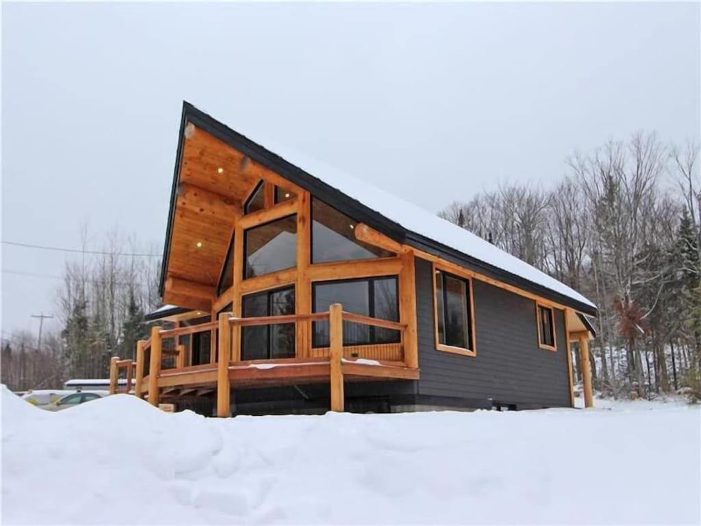Saint-PhilémonLe Billot- Chalet Rustic avec Spa的雪中的一个小木屋,周围积雪环绕