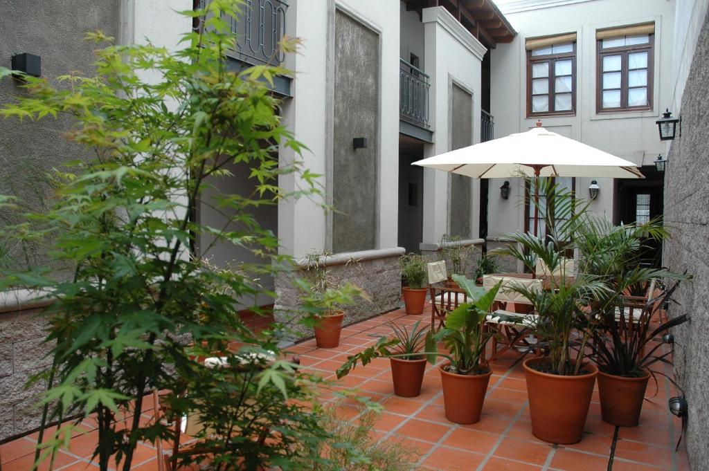 布宜诺斯艾利斯波萨达高登酒店的一个带遮阳伞、椅子和盆栽的庭院