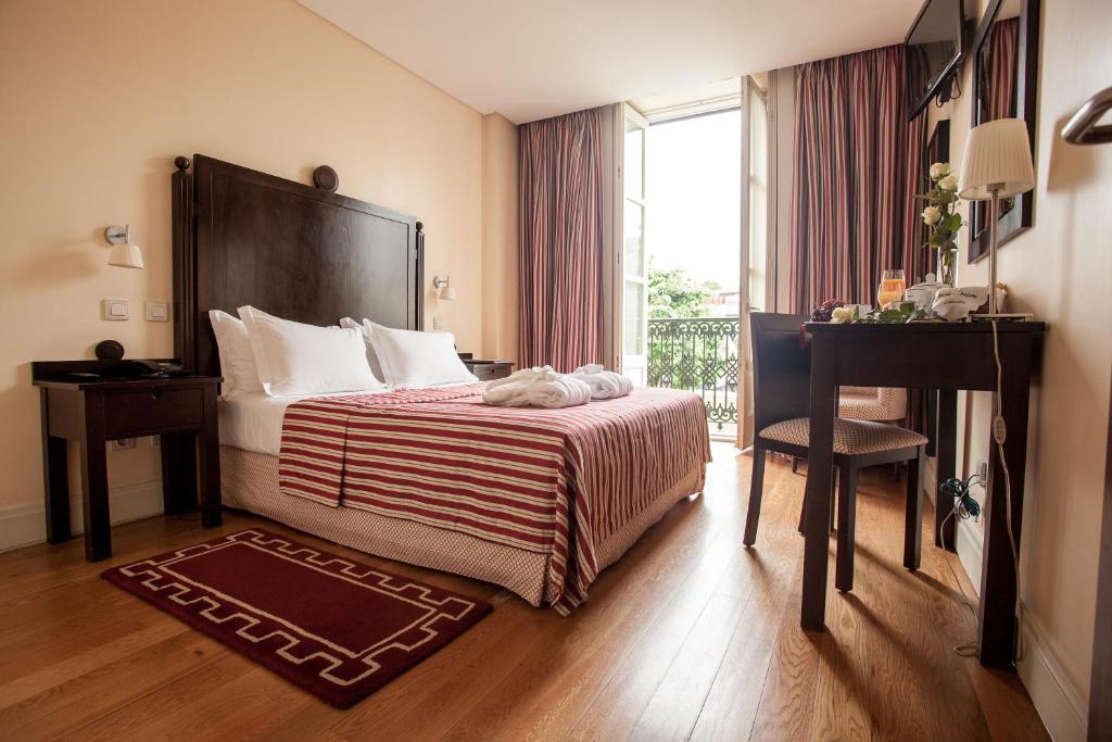 布拉加布拉卡拉奥古斯塔酒店的配有一张床、一张书桌和一扇窗户的酒店客房