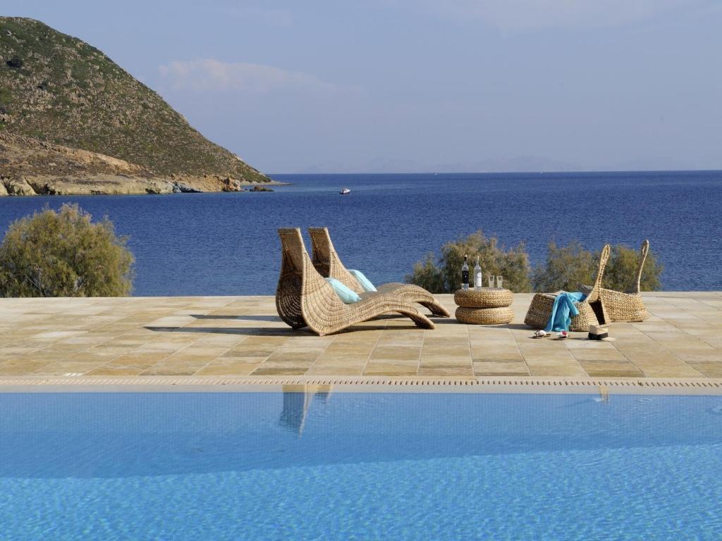 GrikosOnar Patmos的水边的游泳池,配有藤椅