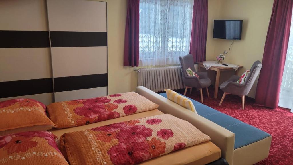 RantenGästehaus Raab的酒店客房带两张床和一张桌子以及椅子。