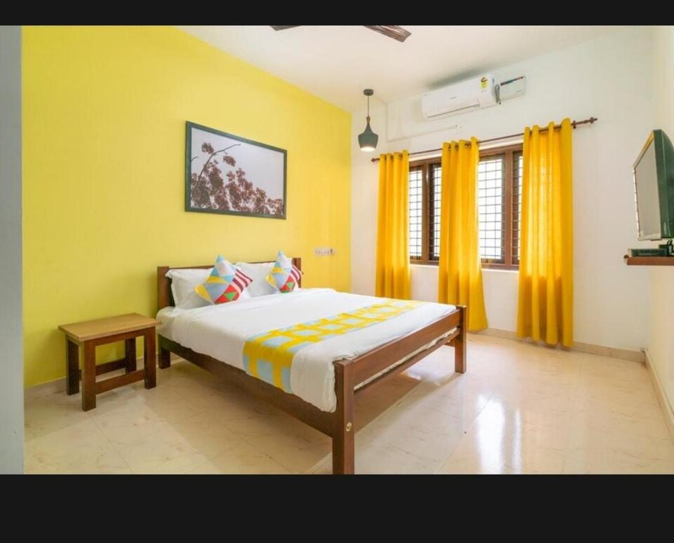 科钦Tharayil Apartments的一间卧室设有一张黄色墙壁的大床