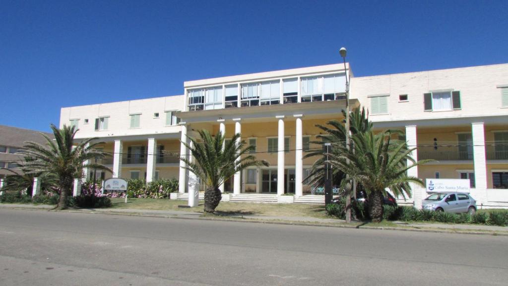 拉帕洛马Hotel Cabo Santa Maria的一座白色的大建筑,前面有棕榈树