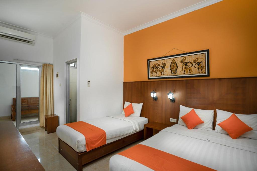 日惹Hotel Poncowinatan - Tugu的酒店客房,设有两张带橙色墙壁的床