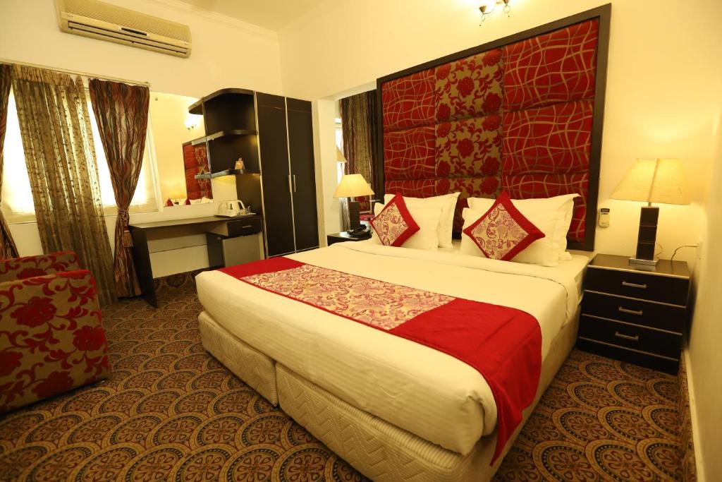 新德里Hotel Capitol Hills - Greater Kailash Delhi的酒店客房设有一张大床和红色床头板