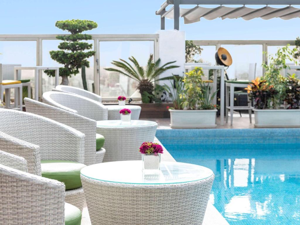 卡萨布兰卡卡萨布兰卡瑞享酒店的一组白色的椅子和桌子,旁边是游泳池