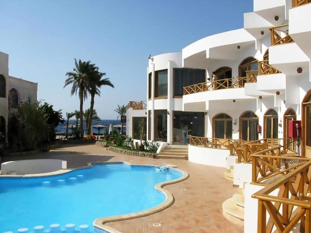 达哈布Red Sea Relax Hotel的一座带游泳池的度假村,位于一座建筑前