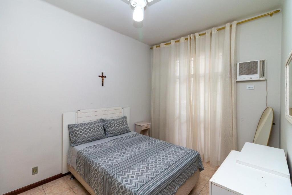 里约热内卢Copacabana Apartamento - Ouro的卧室配有一张床,墙上有十字架