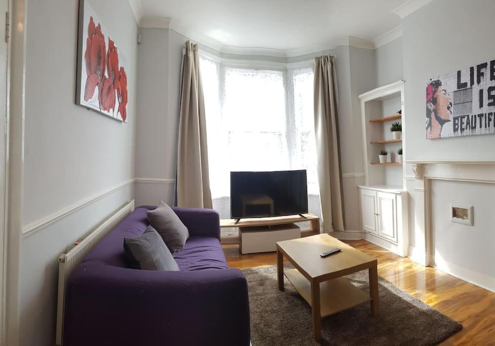 伦敦London. Gorgeous 2 bed flat near Olympic Park.的客厅配有紫色沙发和电视