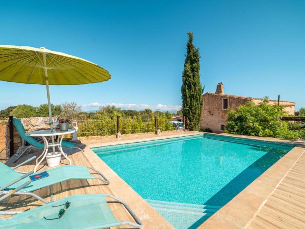 阿尔盖达Villa Can Lloret的一个带桌椅和遮阳伞的游泳池