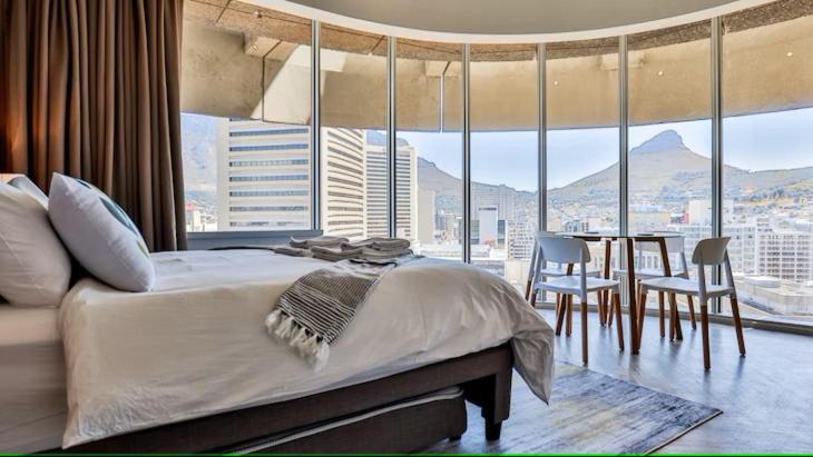 开普敦D'Luxe on Thibault by CTHA的一间卧室配有一张大床和一张桌子及椅子