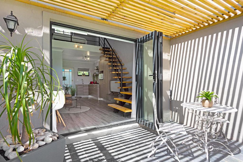 布鲁堡史特兰Blouberg Studio Apartment的天井设有楼梯和植物桌子