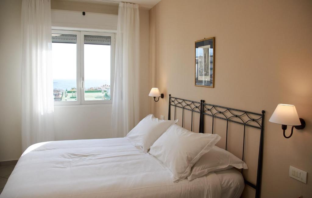 那不勒斯玛格丽特别墅酒店的一间卧室配有一张带白色床单的床和一扇窗户。