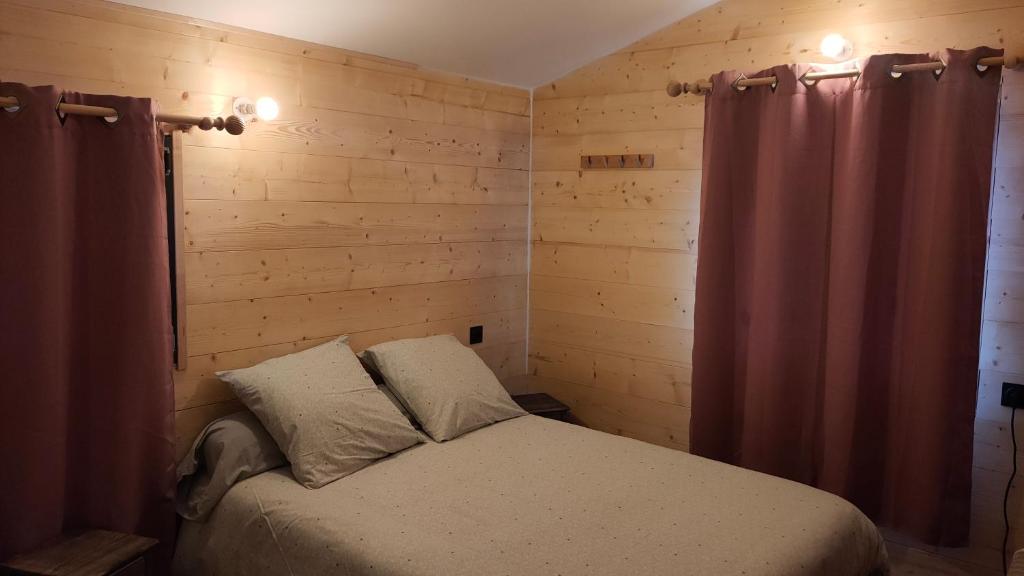 Lepin-le-LacLa tanière du lac d Aiguebelette的卧室配有一张床铺,位于带木墙的房间内